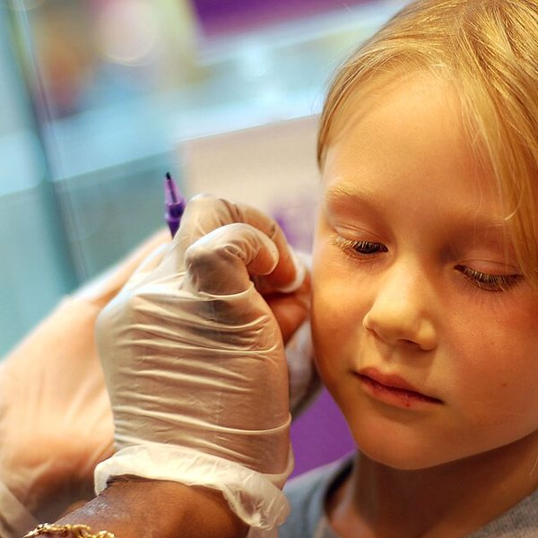 An earlobe being marked before an ear piercing