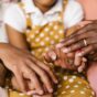 Three generations of family hands held together, the mother and grandmother wearing rings